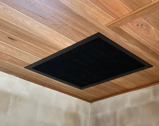 Black return air grille in a timber ceiling