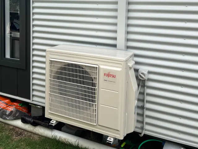 Colour-matched Colourbond pipe cover on a corrugated metal wall