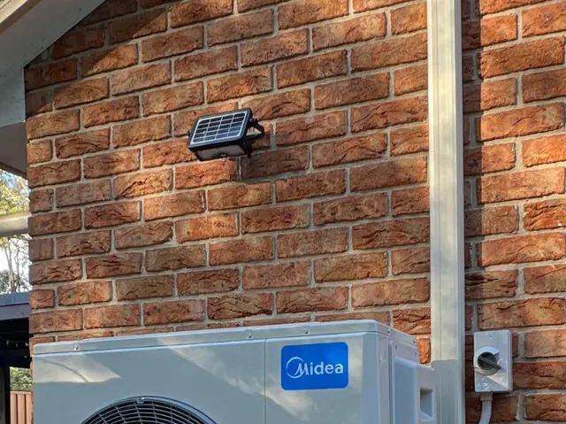 White PVC pipe cover running down a brick wall to an outdoor unit
